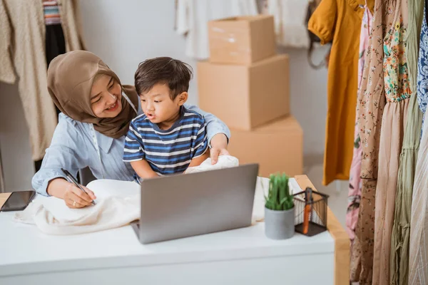 Asian muslim mother taking care of her son while working — Stock Photo, Image