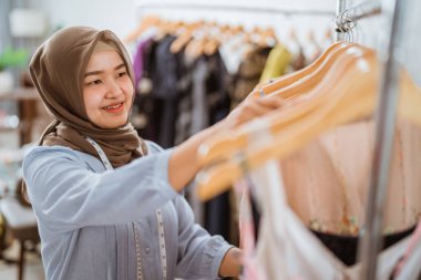 Müslüman moda tasarımcısı elbise ürünlerini kontrol ediyor.