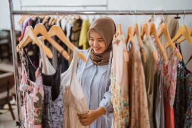Müslüman moda tasarımcısı elbise ürünlerini kontrol ediyor.