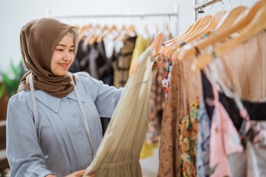 Başarılı Müslüman moda tasarımcısı ürününü kontrol ediyor.