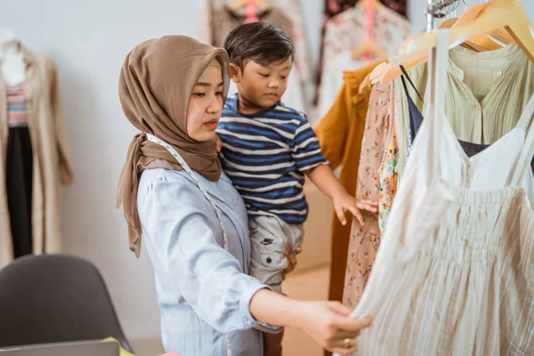 Asijské muslim matka starající se o svého syna při práci — Stock fotografie