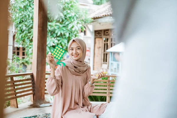 Vrouw draagt hijab glimlachende met diamant vormige papieren decoratie — Stockfoto