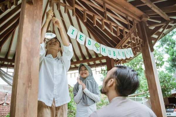 Anak laki-laki kencangkan rantai bendera dengan ayah dan adik dalam gazebo — Stok Foto