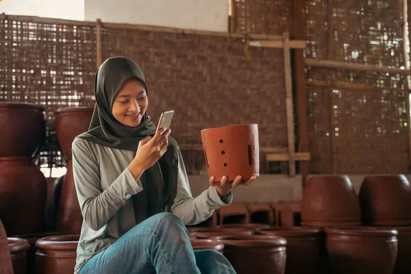 Ragazza in hijab utilizzando la fotocamera del telefono cellulare per fotografare ceramiche — Foto Stock