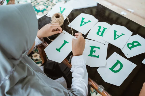 Chica velada haciendo decoración de papel de cadena de bandera para Eid Mubarak — Foto de Stock