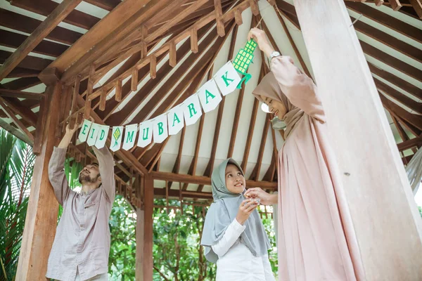 Peçeli kız, kağıt süsleme yaparken anne ve babaya yardım ediyor.