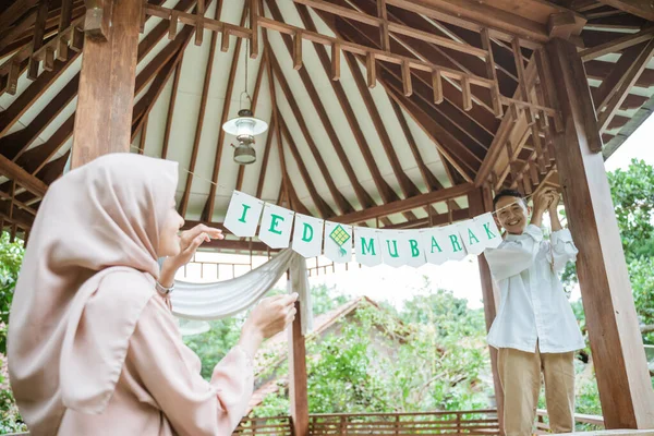 Um menino prende uma corrente de bandeira a um poste de gazebo — Fotografia de Stock