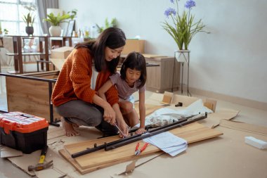 Anne ve kızı yeni mobilya monte ediyorlar.