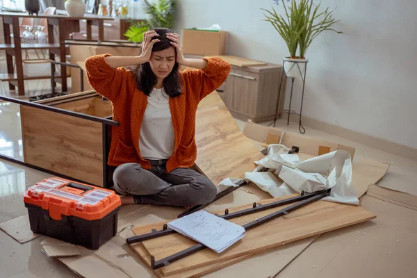 confused woman while assembling new furniture at home