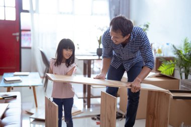 Asyalı baba ve kız evlerinde yeni mobilya monte ediyorlar.