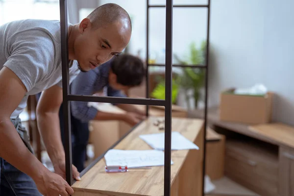 Twee mannelijke houtbewerker monteren nieuw meubilair samen — Stockfoto