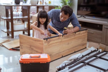 Asyalı baba ve kız evlerinde yeni mobilya monte ediyorlar.