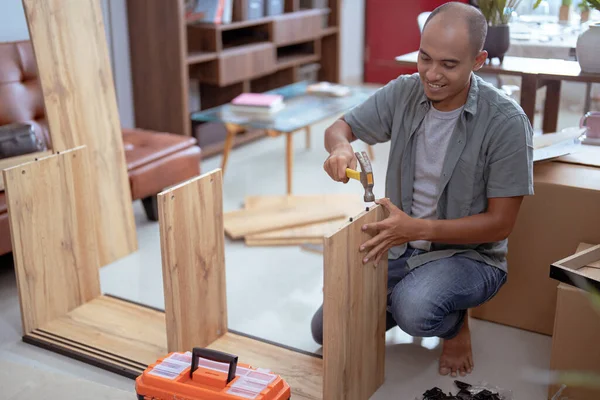 Homem feliz enquanto trabalhava na montagem de novos móveis — Fotografia de Stock