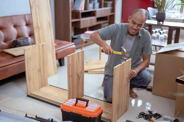 Homem feliz enquanto trabalhava na montagem de novos móveis — Fotografia de Stock