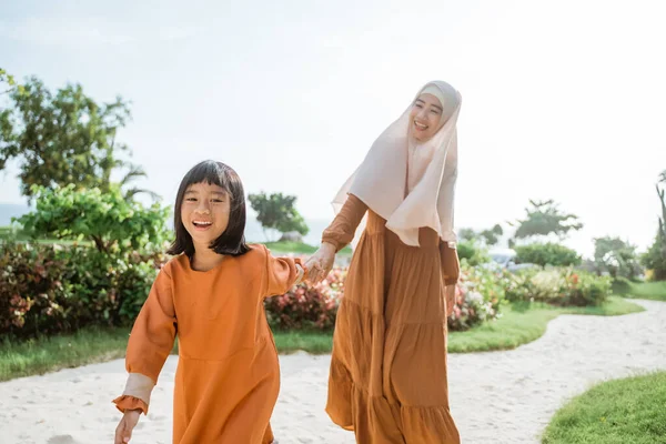 イスラム教徒の母親と娘が一緒に歩いて手を携えて — ストック写真