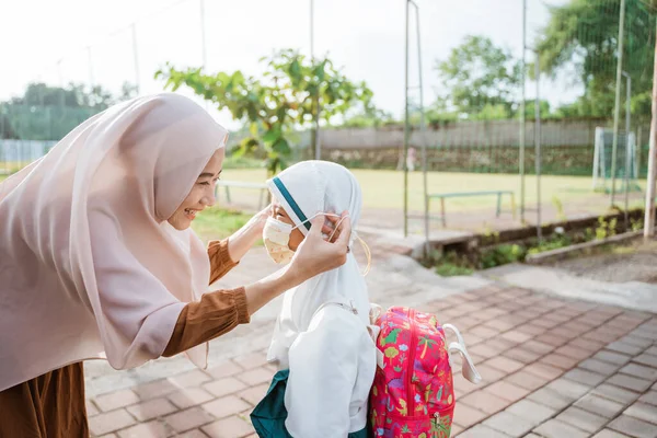 Ibu muslim membantu putrinya untuk mengenakan topeng — Stok Foto