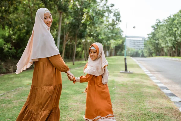 Madre e hija musulmanas caminando y cogiéndose de la mano —  Fotos de Stock