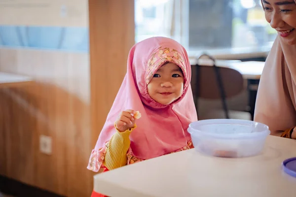 Muslim mladá dívka při posezení na jídelně s matkou s úsměvem na kameru — Stock fotografie