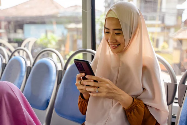 Mulher muçulmana usando telefone celular enquanto sentado em ônibus público — Fotografia de Stock
