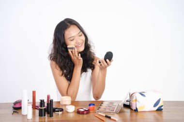 Makyaj pudrası süren ve yanaklarını kızartan bir kadın.