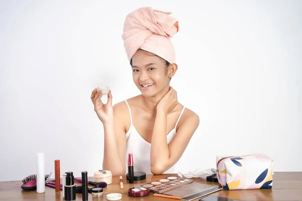 Asian girl applying facial moisturizer while holding jar — Stock Photo, Image