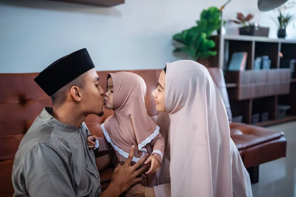 Мусульманская семья целует свою маленькую дочь, веселясь дома — стоковое фото