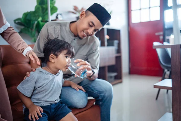 Asiatischer muslimischer Vater hilft seinem Sohn, Wasser zu trinken — Stockfoto