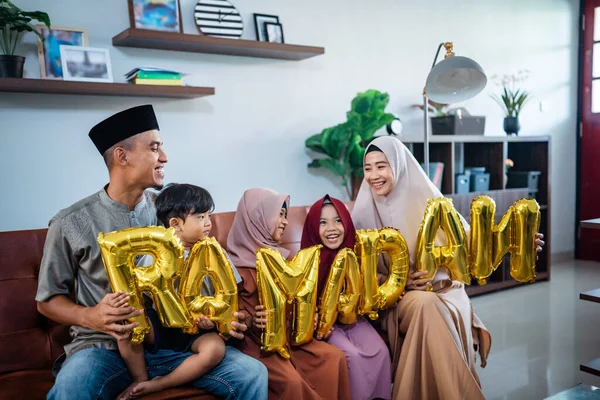 Família vestindo roupas tradicionais muçulmanas segurando um texto do ramadã — Fotografia de Stock