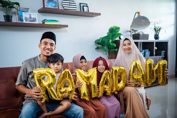 Família vestindo roupas tradicionais muçulmanas segurando um texto do ramadã — Fotografia de Stock