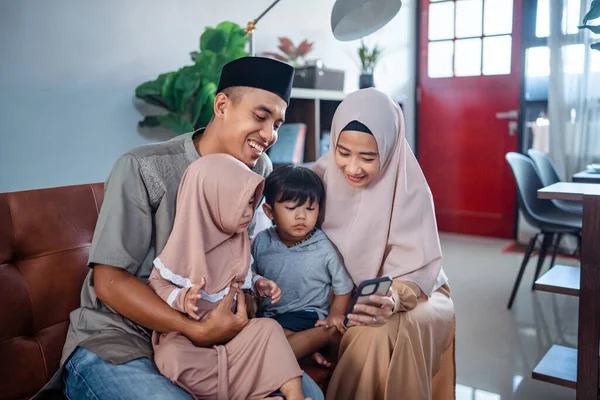 Família muçulmano com duas crianças pequenas olhando para o telefone móvel — Fotografia de Stock