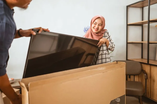 Muslim pár nesoucí ploché televizní obrazovky v jejich moderním domě — Stock fotografie