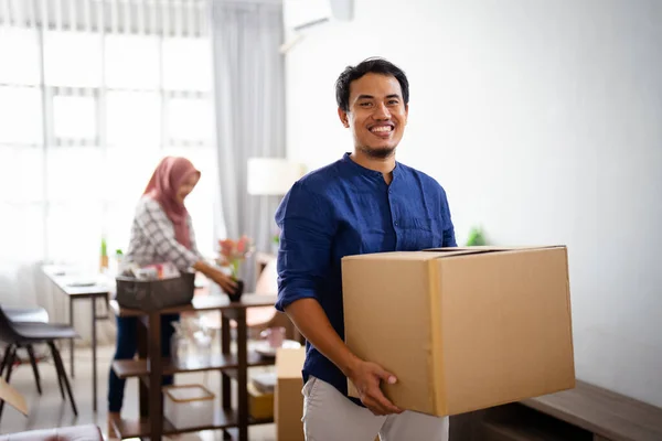 Ung man tittar på kameran medan han bär sin kartong — Stockfoto