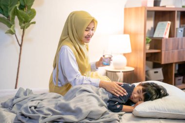 muslim mother waking her daughter up in the bed clipart