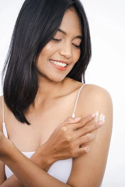 Jovem mulher aplica creme em seu braço. Em um fundo branco. — Fotografia de Stock