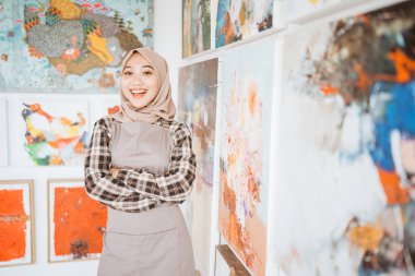 Müslüman kadın ressam atölyesinde tuvale resim yapıyor.