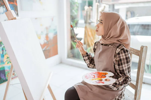 Asiático musulmán mujer artista empezar a pintar en blanco lienzo —  Fotos de Stock