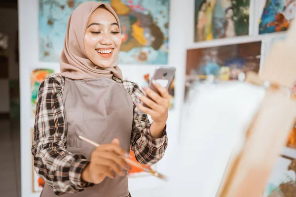 Artista femenina musulmana en busca de inspiración de su teléfono móvil —  Fotos de Stock