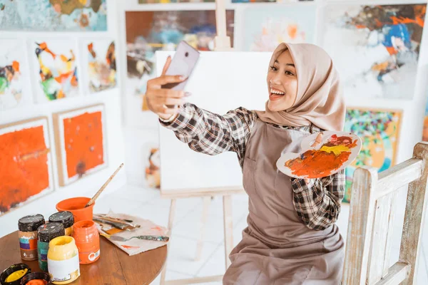 Muslim artista femenina tomando foto selfie con su propia pintura —  Fotos de Stock
