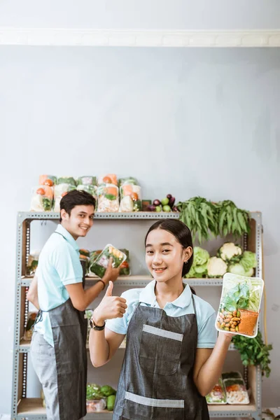 Δύο χαμογελαστοί πωλητές λαχανικών με αντίχειρες στον πάγκο με τα λαχανικά — Φωτογραφία Αρχείου