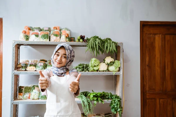 Dziewczyna w hidżabie sprzedaje warzywa z dwoma kciukami w górze — Zdjęcie stockowe