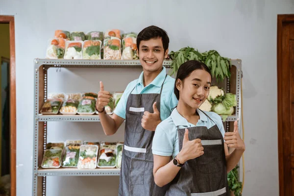 Усміхнені асистенти жіночого і чоловічого магазину з великими пальцями вгору — стокове фото