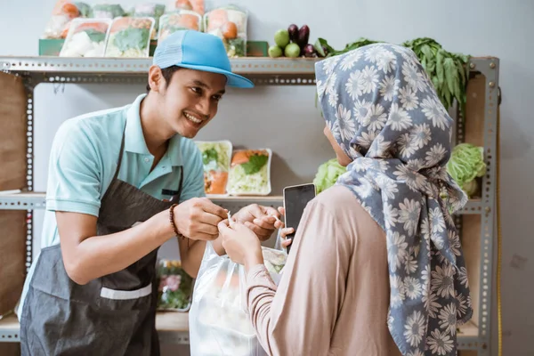 Vendedores de verduras dan bolsas de plástico a los clientes que hacen compras no monetarias — Foto de Stock