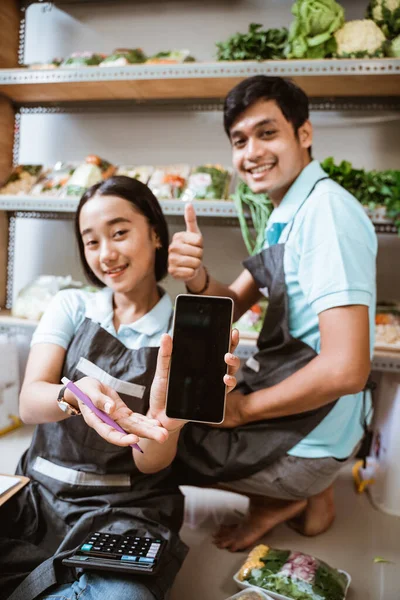 Δύο πωλητές λαχανικών που δείχνουν την οθόνη ενός τηλεφώνου — Φωτογραφία Αρχείου