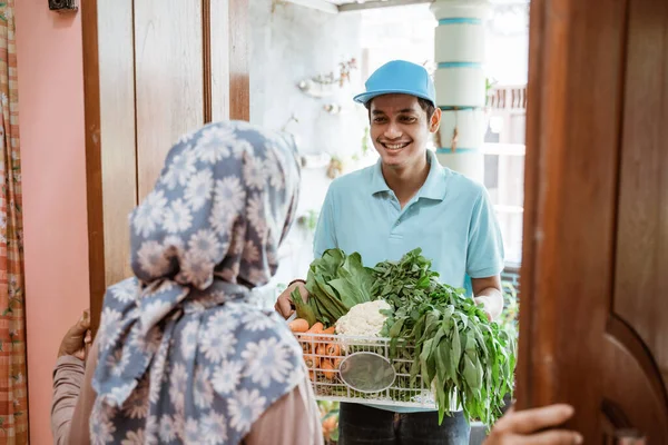 Deliveryman en uniforme entrega orden de verduras frescas al cliente — Foto de Stock