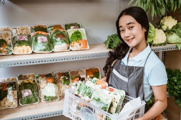 Glimlachend aziatisch meisje dragen schort dragen mand van verse groenten — Stockfoto