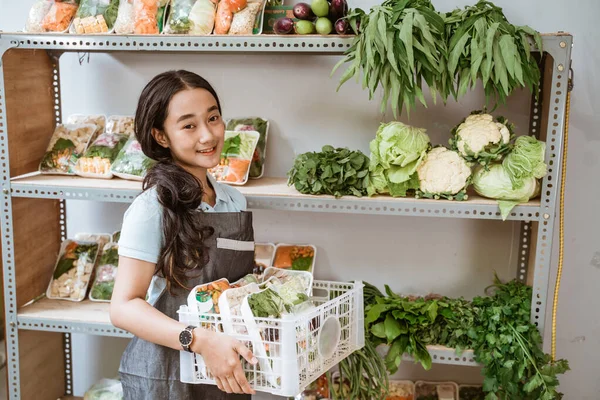 Schattig meisje met een schort vol verse groenten — Stockfoto