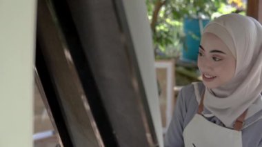 Müslüman Asyalı kadın ressam tuval üzerinde resim yapıyor.