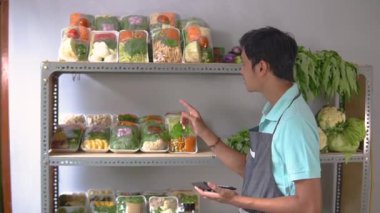 Sebze satan adam hesap makinesi kullanarak sebze sayıyor.