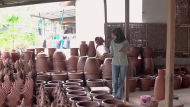 Pedi kullanırken çömlekçiliğe bakan örtülü iş kadını