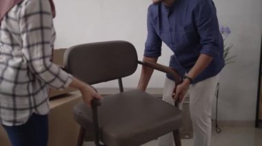 Müslüman genç çift yeni evlerinde yeni sandalye taşıyorlar.